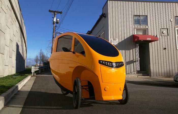 Veemo Velomobile, yellow, tilted, in the street.