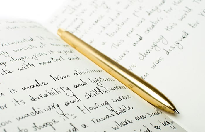 Gold SENS Pen On A Notebook With Writings On It