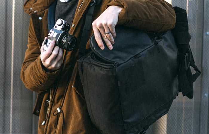 A Guy Placing A Camera Into PRVKE Travel and DSLR Camera Backpack