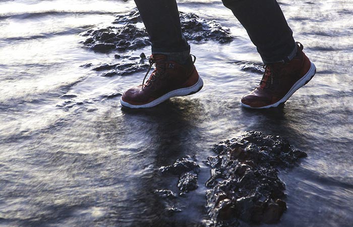 Man traversing water with a pair of Arrowood Luc Mid Hikers