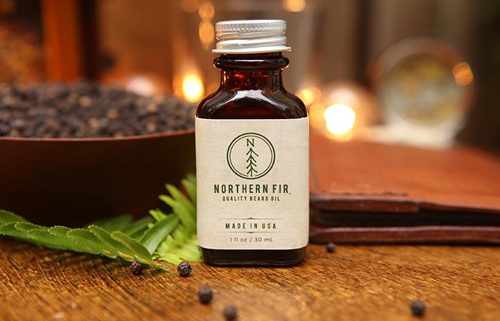 Shot of Norther Fir Beard Oil on a table with some pepper and cedarwood