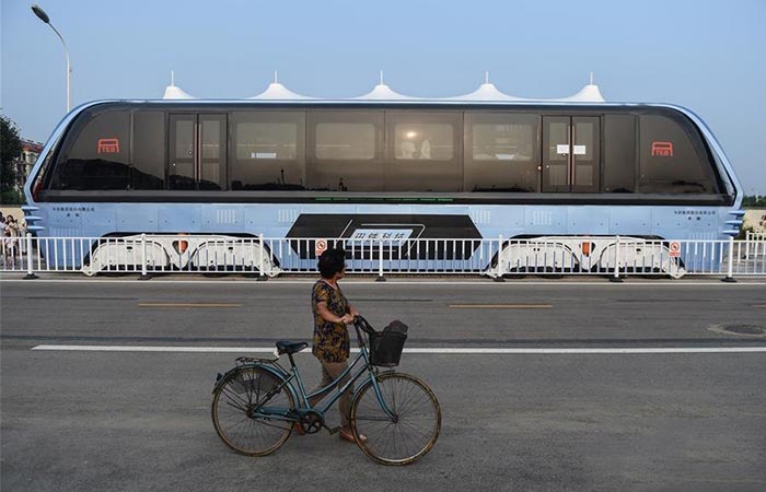 World’s First Transit Elevated Bus side view with a woman walking with her bicycle