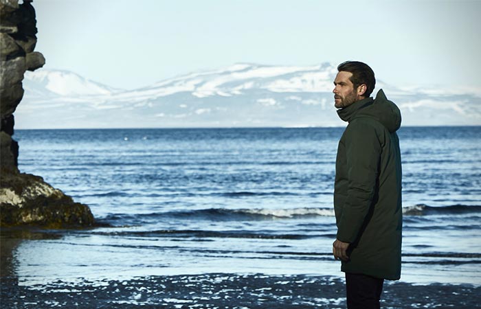 A Guy Standing Next To The Water In Aether Apparel’s Tromso Jacket