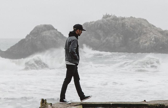 A Guy Walking Next To Water In Iron And Resin X Huckberry Rambler Jacket