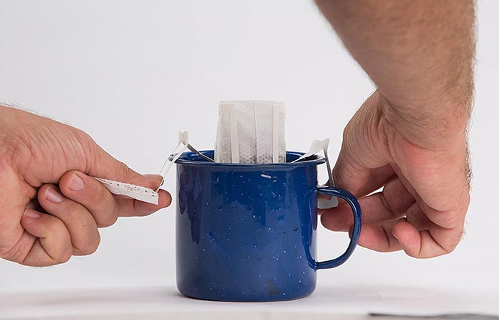 Man attaching Libra Pourtable coffee bag to the sides of the mug