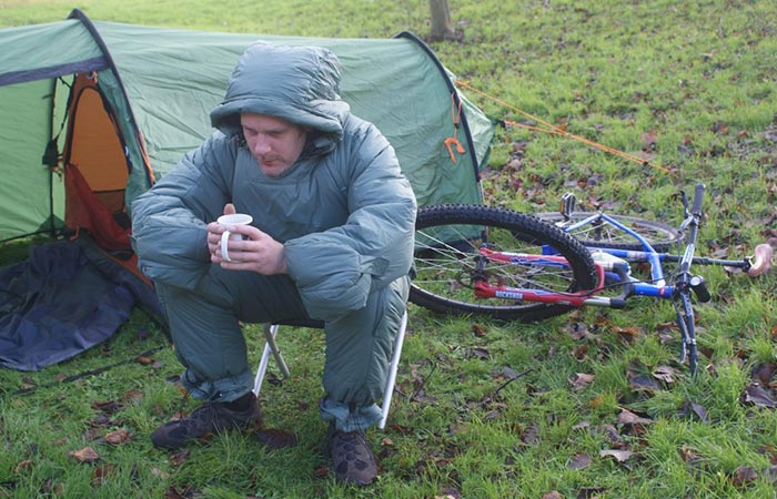 Selk’bag Patagon Duck Green being worn by a man drinking coffee next to a tent