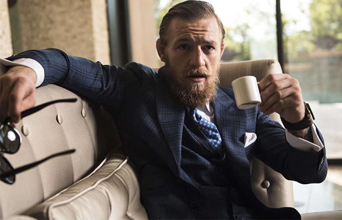 Conor wearing a suit and drinking coffee
