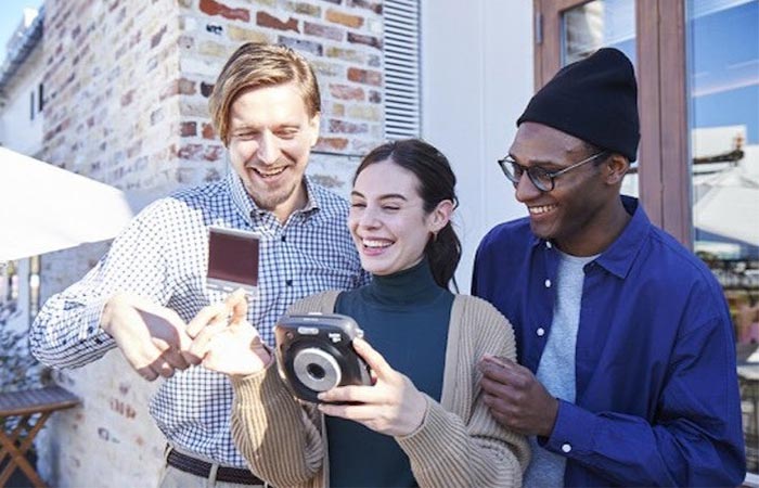 three people using an instant camera