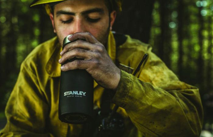 a guy drinking from black stanley vaccum bottle